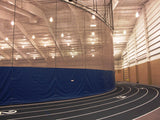 Curved blue and mesh gymnasium curtain separating a running track from an interior space.