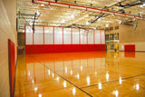 Red and white fold-up gymnasium curtain dividing a basketball court.