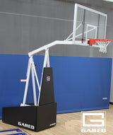 Portable basketball hoop with clear backboard, orange rim, and white net on a gym floor.