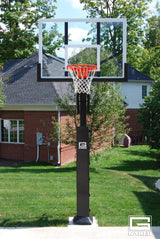 Adjustable basketball hoop with clear acrylic backboard and orange rim in a backyard setting.