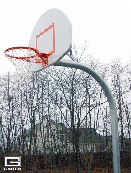 White basketball backboard with orange rim and net on a gray gooseneck pole, trees and house in background.