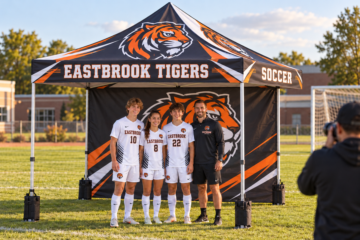 School athletes pose for a photographer in front of a custom printed tent wall.