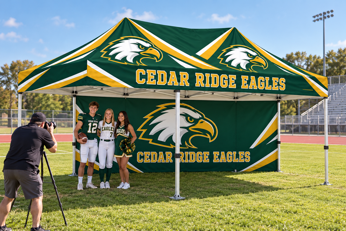 School athletes pose for a photographer in front of a custom printed tent wall.
