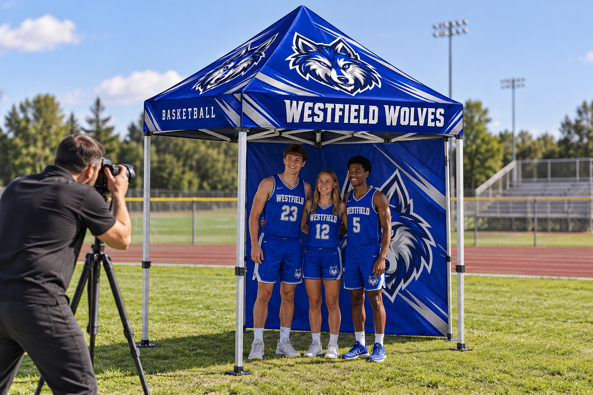 School athletes pose for a photographer in front of a custom printed tent wall.