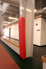 Red I-beam wall pad installed on a white column in a hallway with a track.