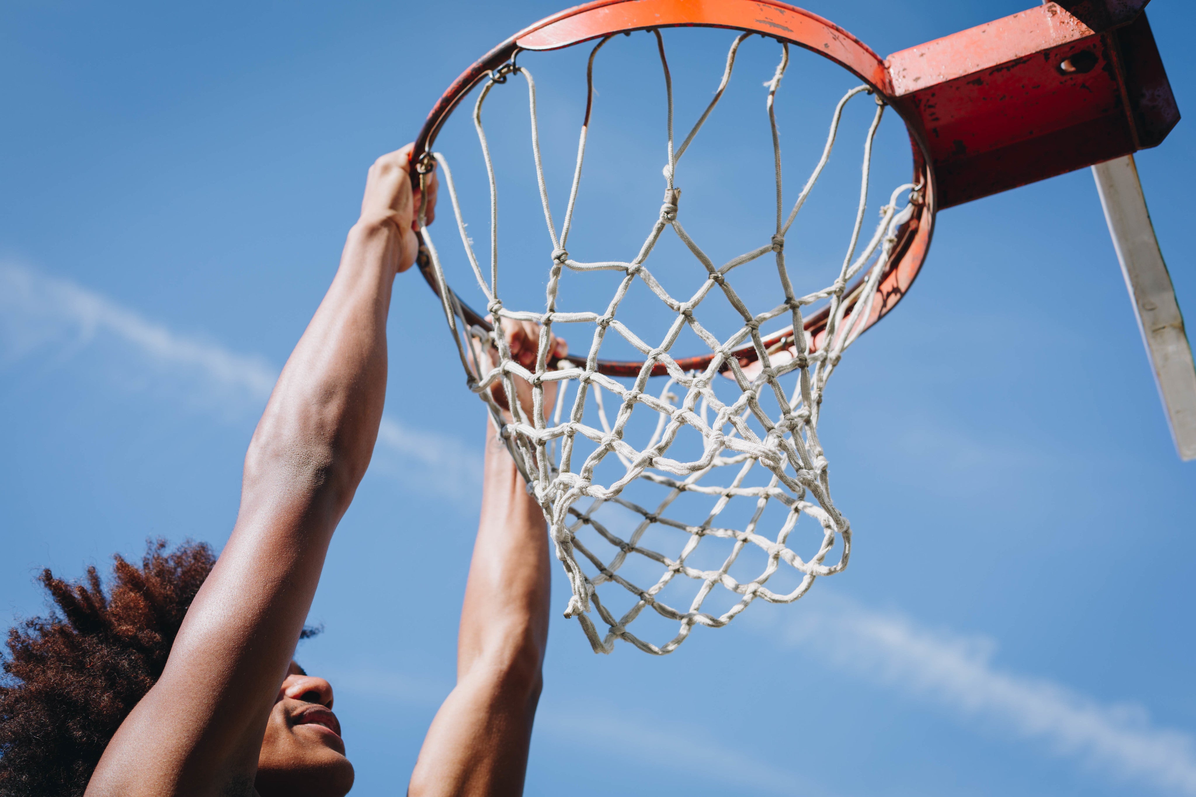 Basketball player hanging from the rim after a dunk during a game