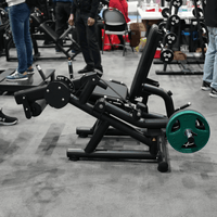 Thumbnail for Black plate-loaded leg extension/curl machine with a green weight plate in a gym setting.