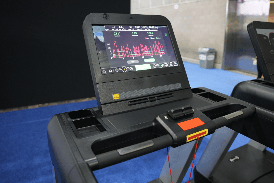 Close-up of a black treadmill console with a large touchscreen displaying a workout graph and controls.