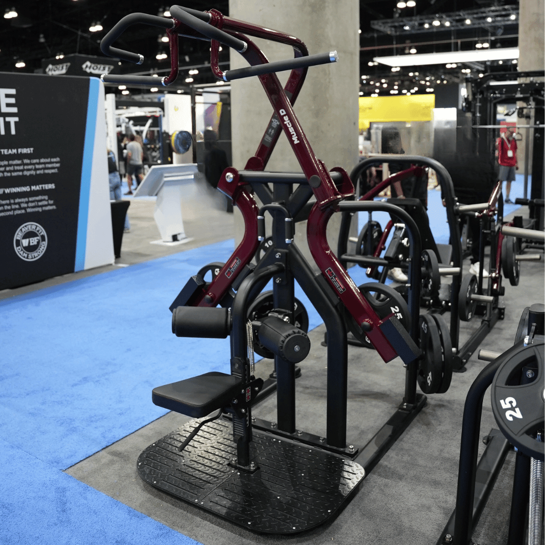 Maroon and black rotary lat pull-down machine with a seat and footplate.