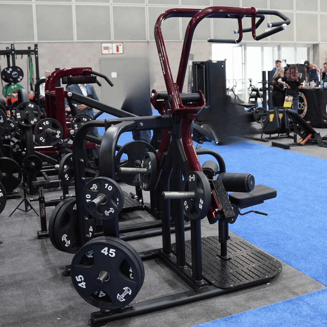 Red and black plate-loaded lat pulldown machine with weight plates in a gym setting.
