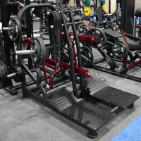 Thumbnail for Plate-loaded belt squat machine with a black belt and foot platforms, in a gym setting.