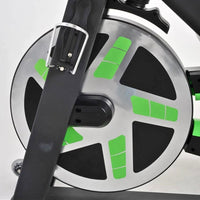 Thumbnail for Close-up of exercise bike flywheel with green accents, black pedal arm, and water bottle holder.