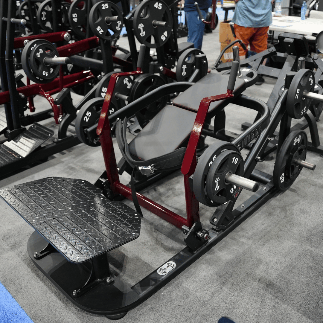 Black and red plate-loaded hip thruster machine with a textured footplate and weight plates.