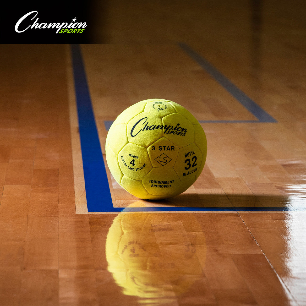 Yellow Champion Sports indoor soccer ball on a polished wood court with blue lines.
