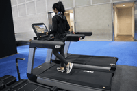 Thumbnail for Woman running on a commercial treadmill with a large touchscreen displaying a scenic route.