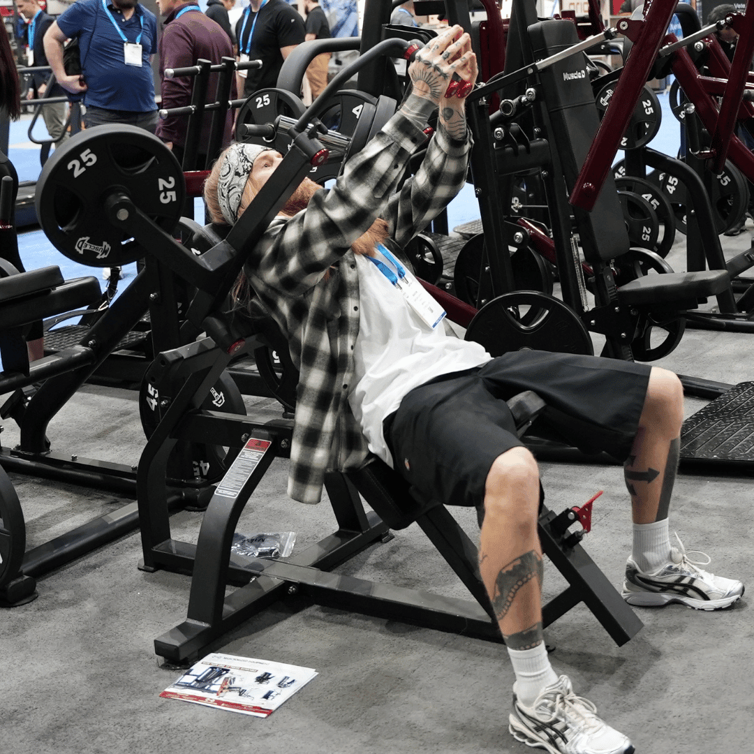 Man with tattoos and bandana using a plate-loaded incline pec fly machine.