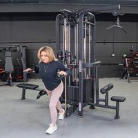 Thumbnail for Woman using a black 4-stack jungle gym machine with multiple pulleys and weight stacks in a gym.