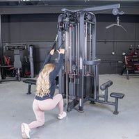 Thumbnail for Woman doing a kneeling lat pulldown on a 4-stack jungle gym with multiple pulleys and weight stacks.