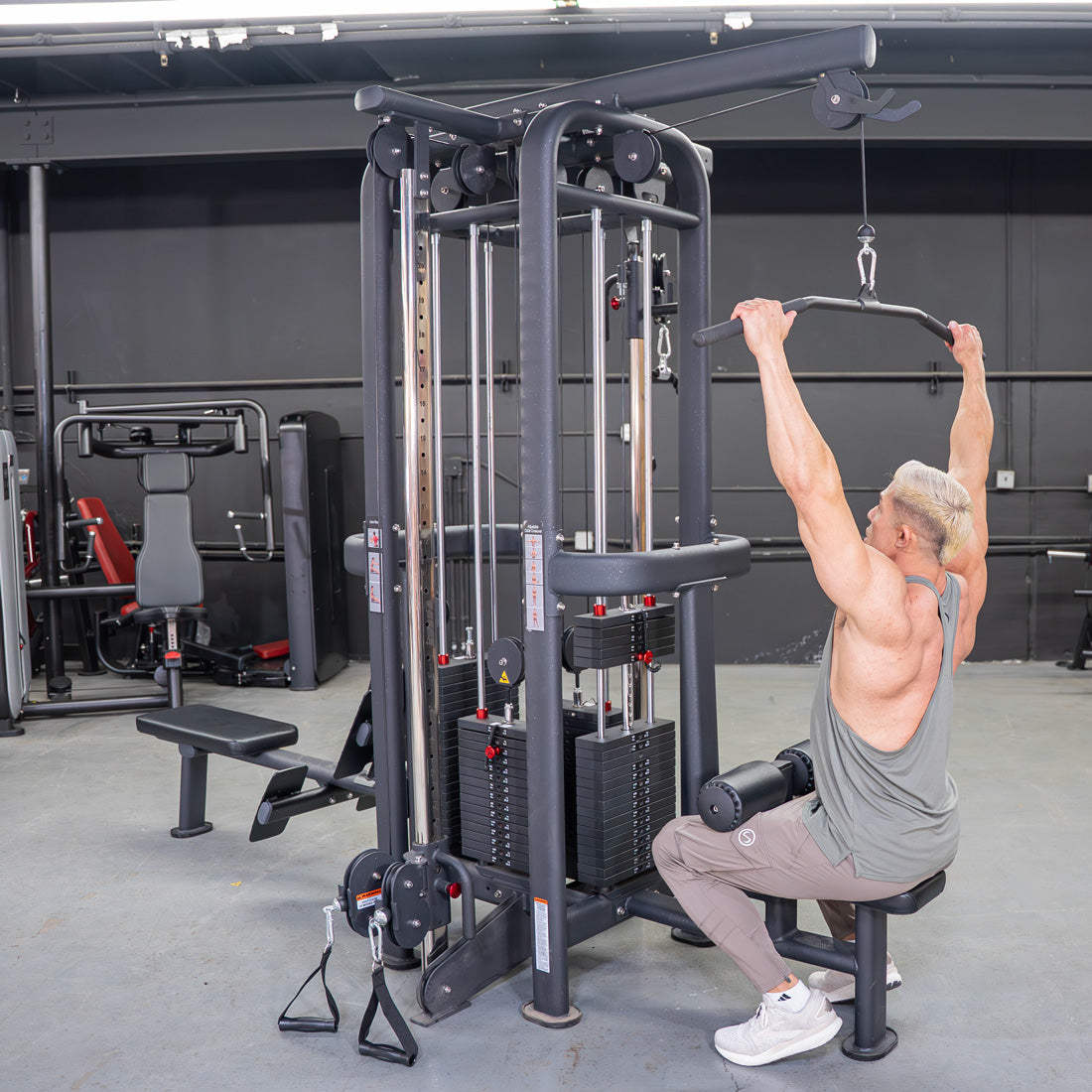 Man doing lat pulldown on a 4-stack jungle gym with multiple pulleys and weight stacks in a gym.