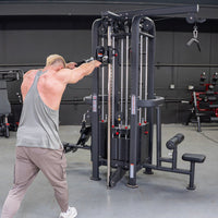 Thumbnail for Muscular man in a grey tank top using a black 4-stack jungle gym machine with multiple pulleys and weight stacks.