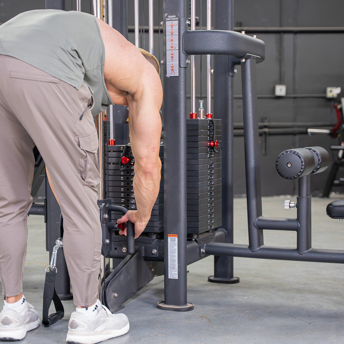 Man adjusting weight stack on a multi-station jungle gym with low row, lat pulldown, and pulley attachments.