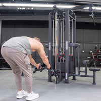 Thumbnail for Muscular man in a gym adjusting the handle on a black 4-stack jungle gym machine with weight stacks.