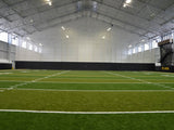 Black gymnasium curtain installed above a green turf field with white markings.