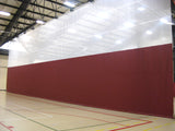 Red and white top-roll gymnasium curtain dividing a gym floor with court lines.