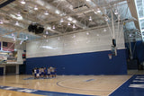 Blue gymnasium curtain with white upper netting dividing a basketball court where players huddle.