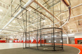 Black suspended throwing cage with netting in a large indoor sports facility.