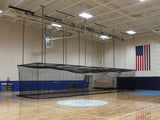 Black mesh multi-sport cage suspended from the ceiling in a gymnasium with a basketball hoop and US flag.