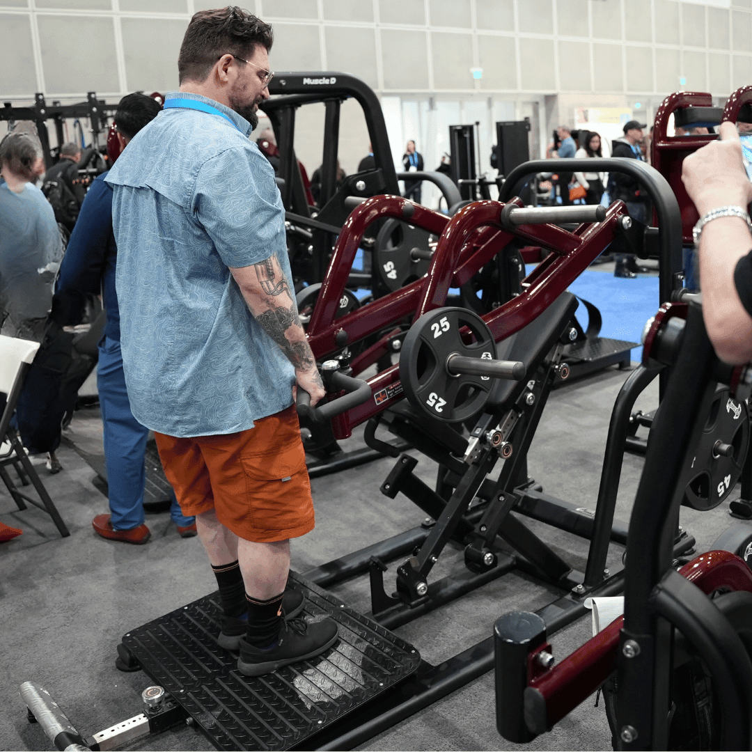 Man using a chest-supported plate-loaded row machine with 25lb weights in a gym.