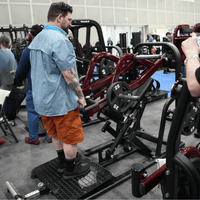 Thumbnail for Man using a chest-supported plate-loaded row machine with 25lb weights in a gym.