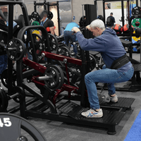 Thumbnail for Man performing a belt squat on a plate-loaded machine in a gym.
