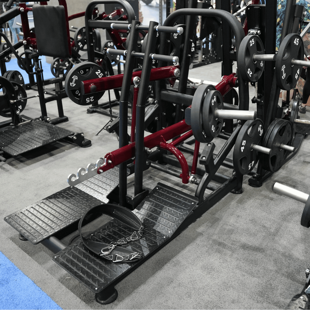 Plate-loaded belt squat machine with a black belt and chain on the footplates.