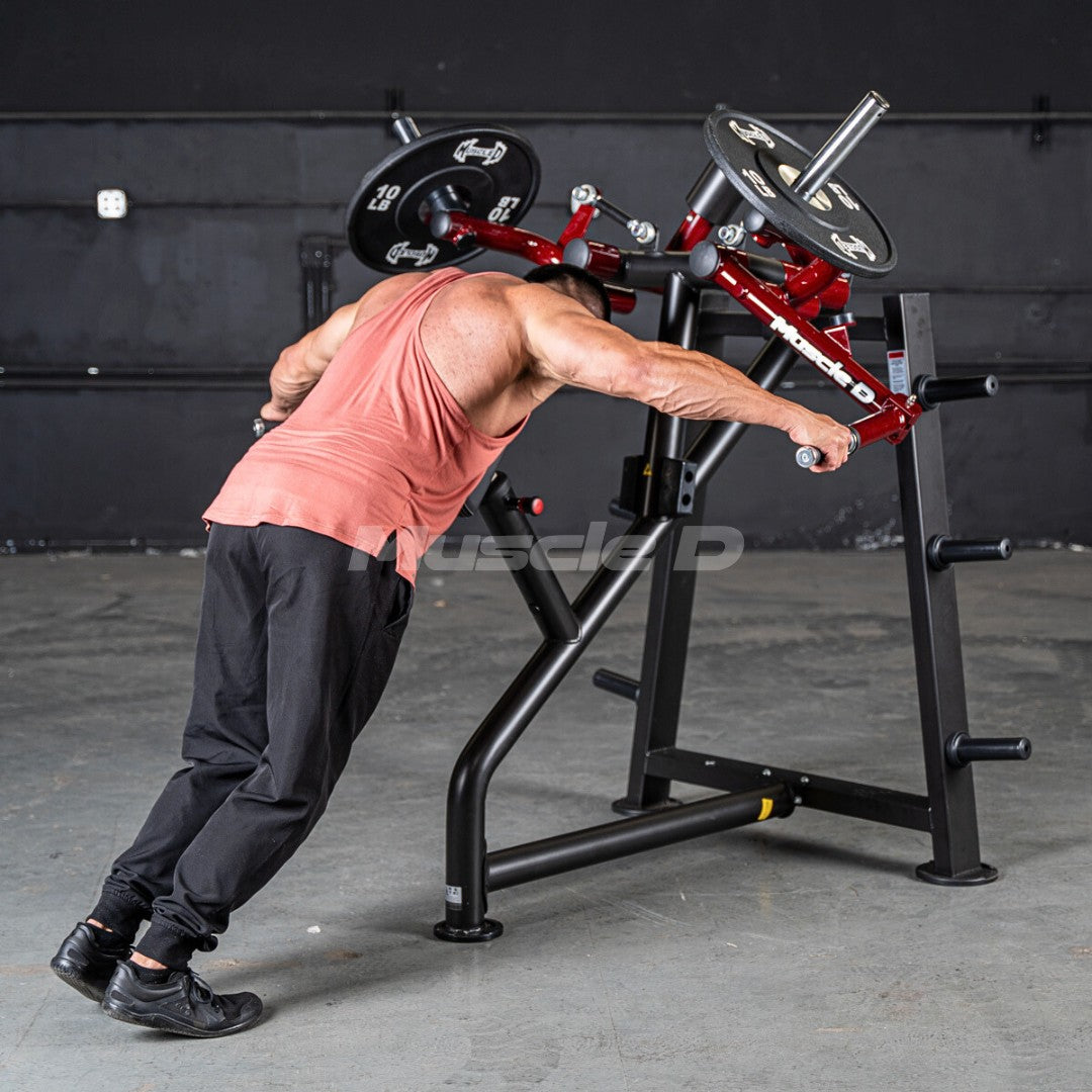 Man in a tank top using a red and black rear delt machine with weight plates in a gym.