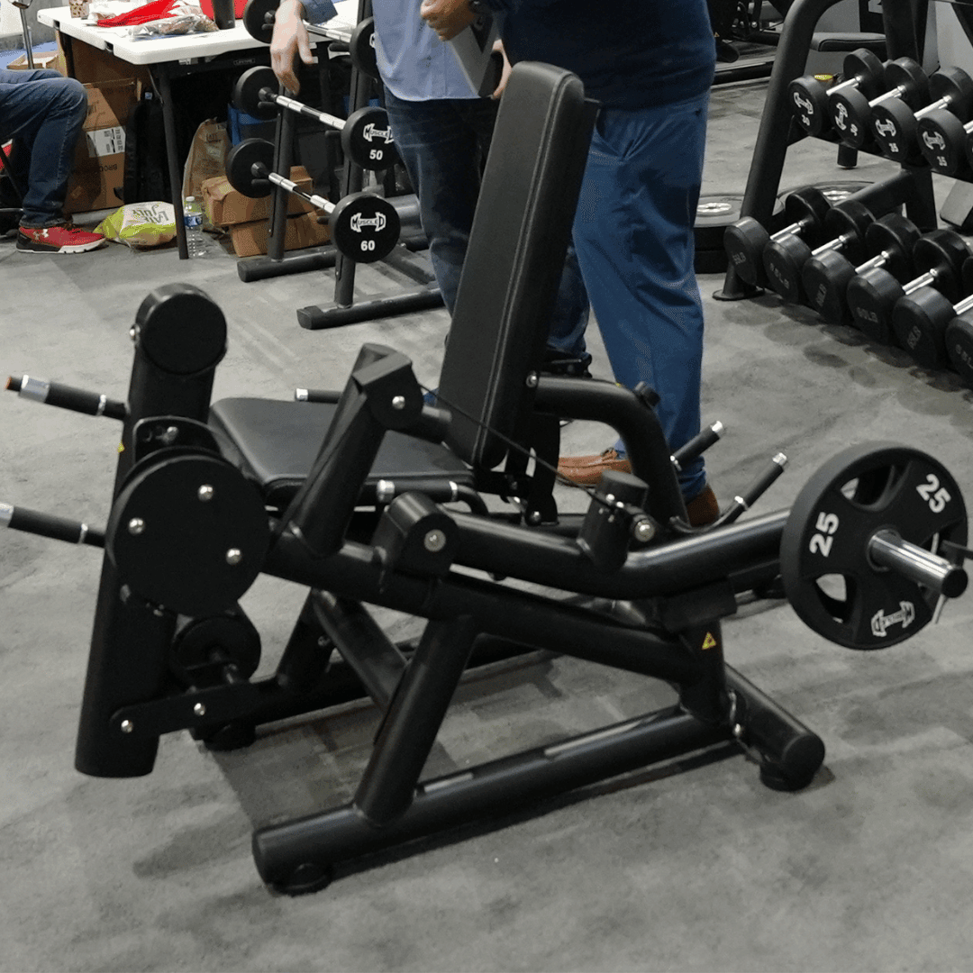 Black plate-loaded leg extension/curl machine with a 25lb plate, in a gym setting.