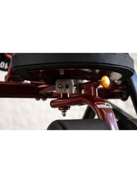 Thumbnail for Close-up of a red fitness machine's black seat, yellow adjustment knob, and padded leg rests.