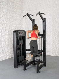Thumbnail for Woman in red top and black leggings using a black assisted chin/dip machine.