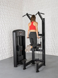 Thumbnail for Woman in red top and black leggings using a black assisted chin/dip machine.