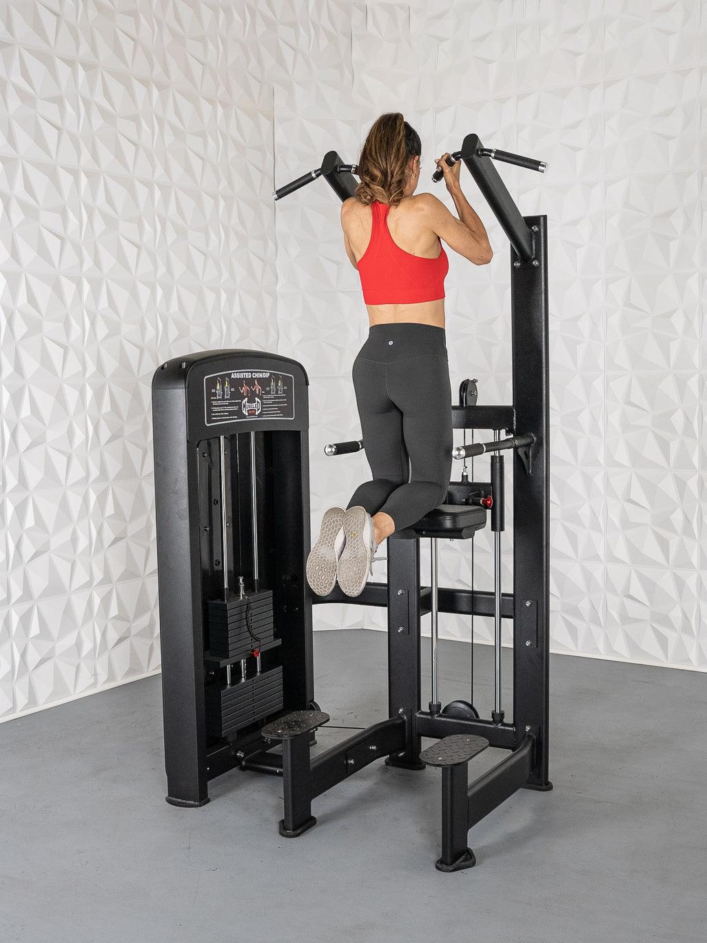 Woman in red top and black leggings using a black assisted chin/dip machine.