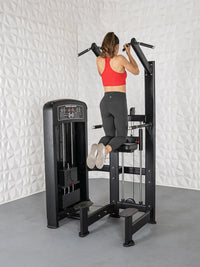 Thumbnail for Woman in red top and black leggings using a black assisted chin/dip machine.
