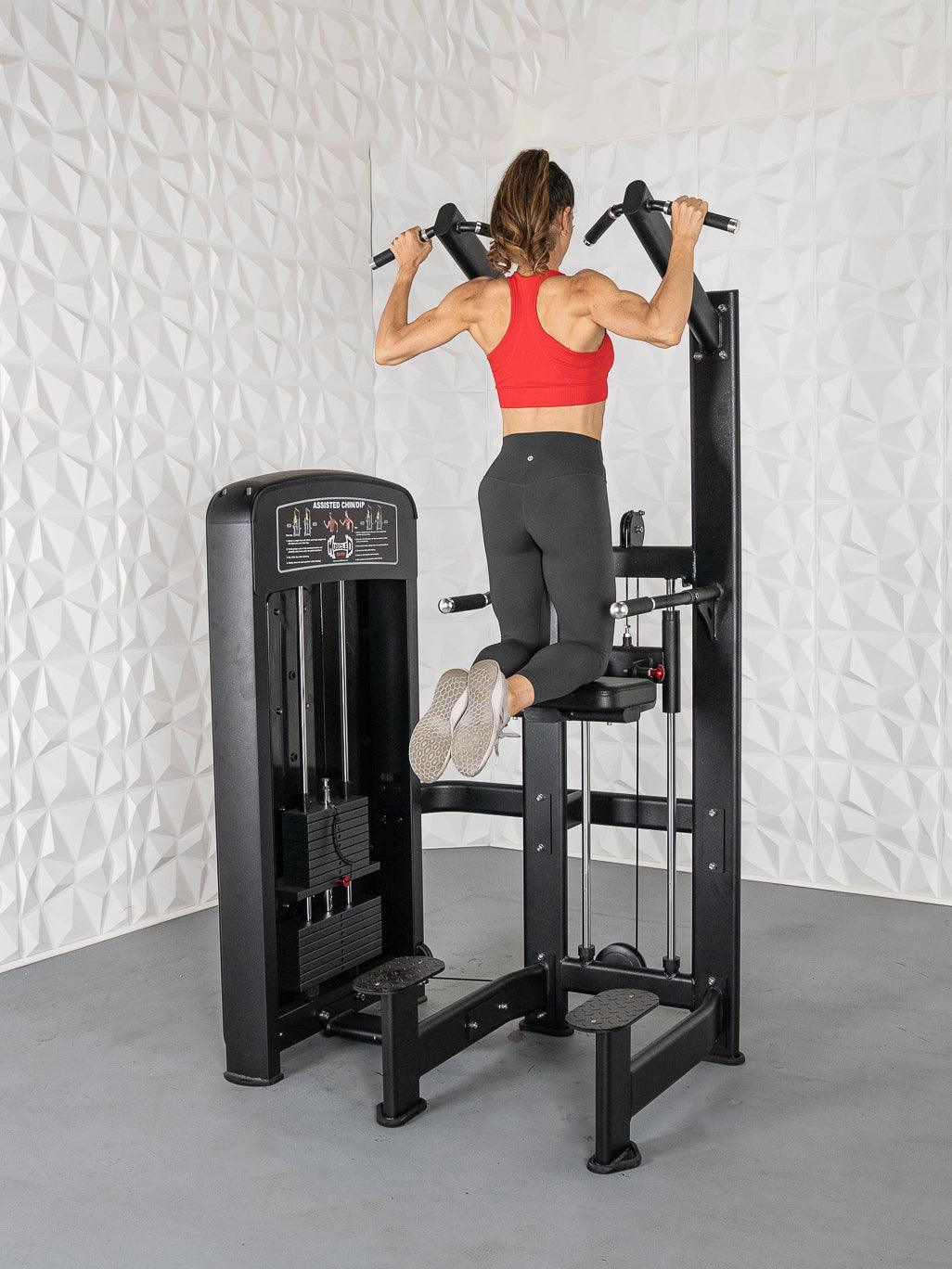 Woman in red top and black leggings using a black assisted chin/dip machine.