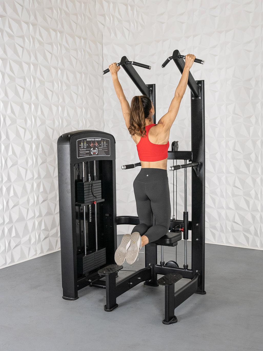 Woman in red top and black leggings using a black assisted chin/dip machine.