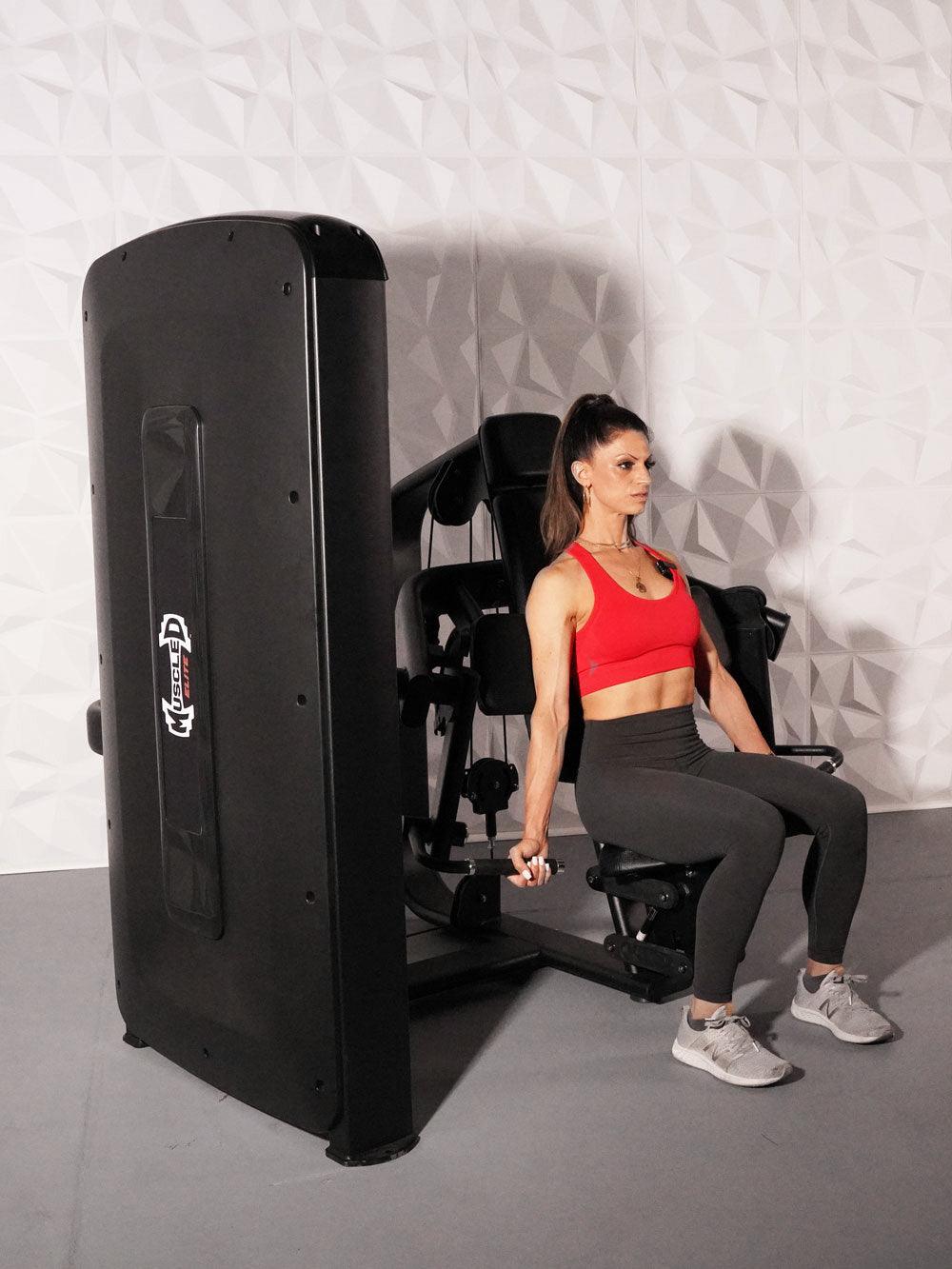 Woman in red top and black leggings using a black selectorized biceps curl machine.
