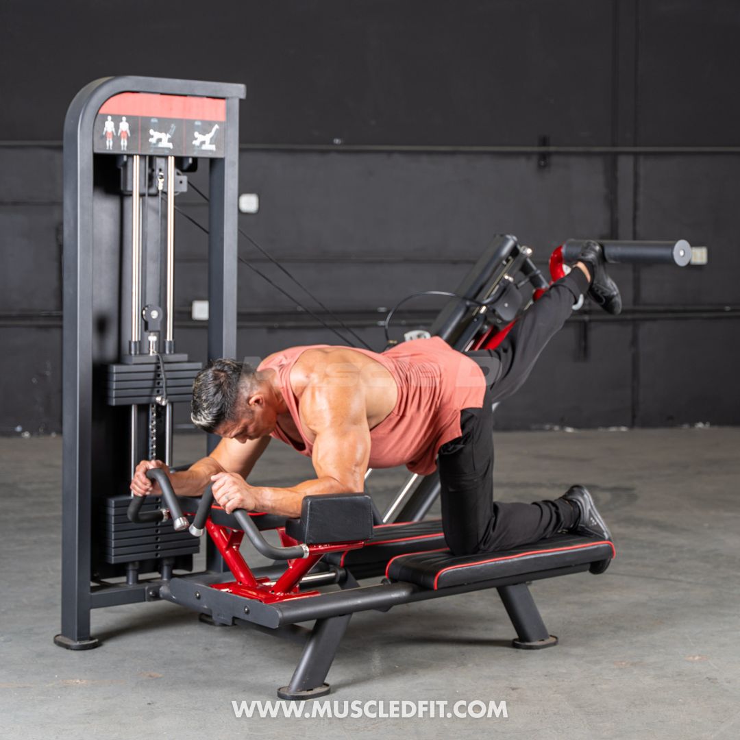 Man using a black and red glute kickback machine, extending his right leg back against a padded bar.