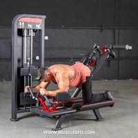 Thumbnail for Man using a black and red glute kickback machine, extending his right leg back against a padded bar.