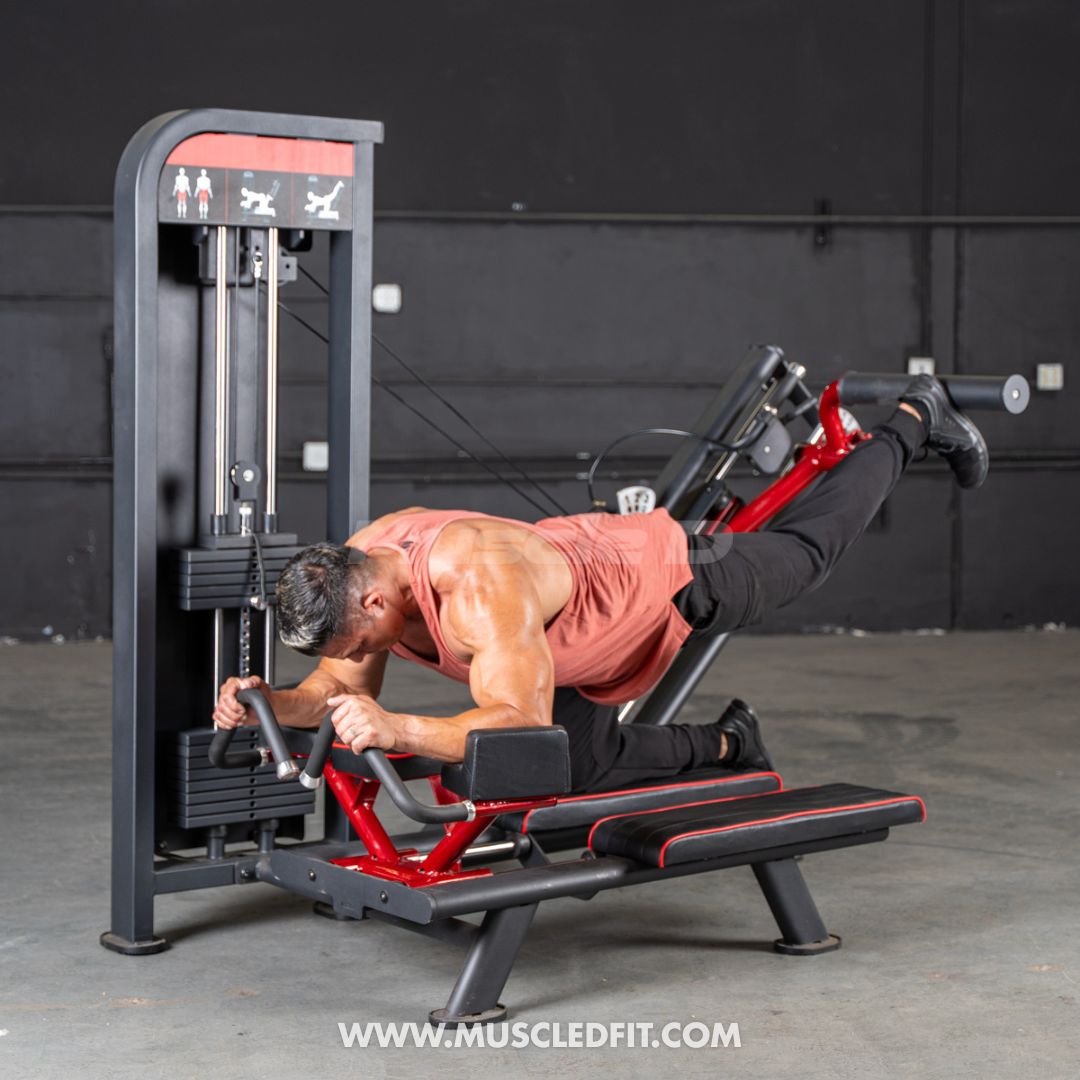 Man using a red and black selectorized glute kick machine in a gym.