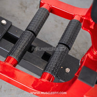 Thumbnail for Close-up of black textured thigh pads on a red fitness machine.