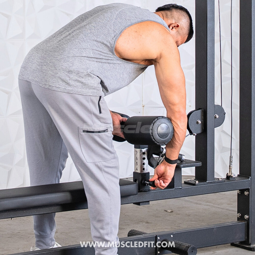 Man adjusting the knee pad height on a black lat pulldown and low row combo machine.